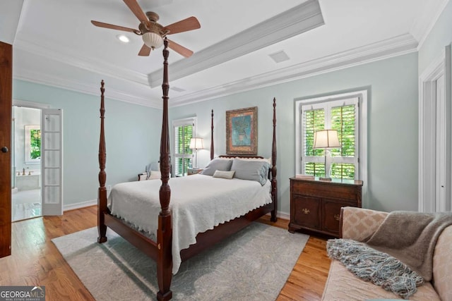 bedroom featuring ornamental molding, a tray ceiling, baseboards, light wood finished floors, and ceiling fan