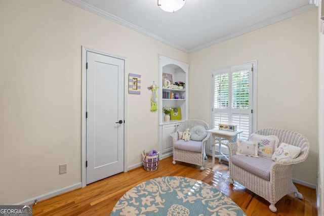 living area featuring crown molding, wood finished floors, and baseboards