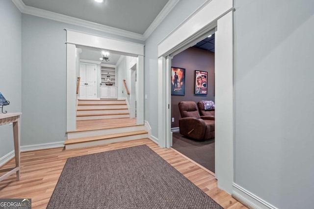 hallway featuring wood finished floors, ornamental molding, baseboards, and stairs