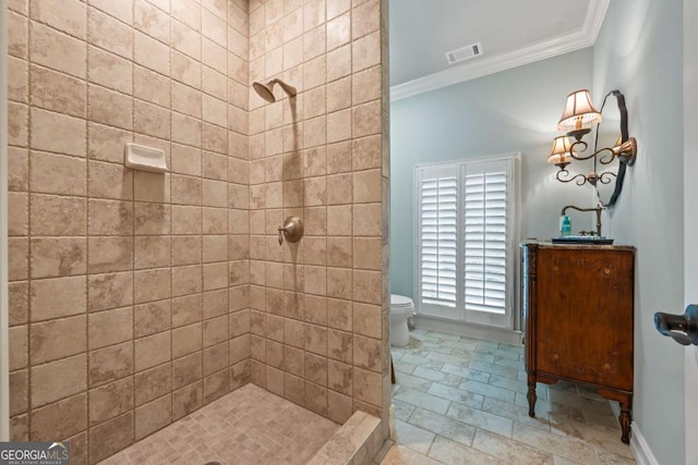 bathroom with crown molding, a tile shower, and toilet