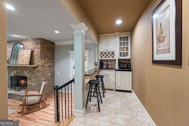 kitchen featuring black microwave, dark countertops, a fireplace, backsplash, and glass insert cabinets