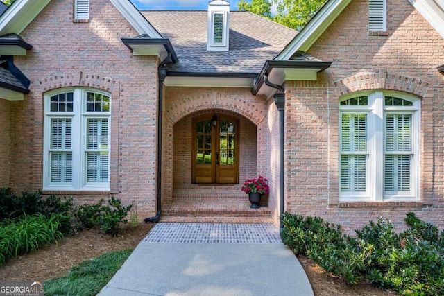 property entrance with roof with shingles and brick siding