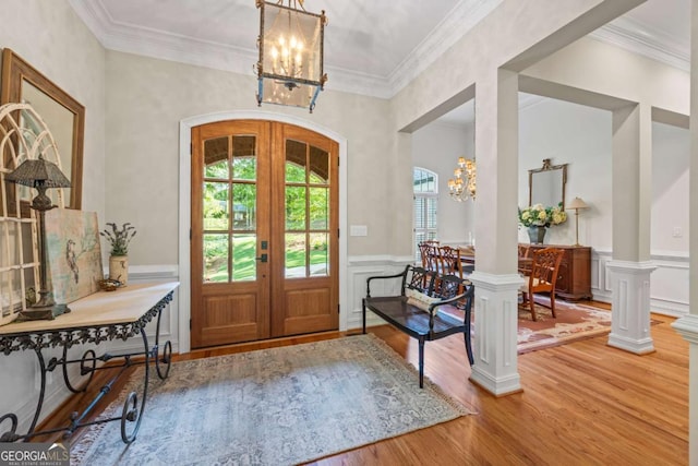 entrance foyer with a chandelier, plenty of natural light, french doors, wood finished floors, and wainscoting