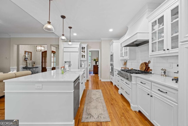 kitchen featuring stainless steel appliances, decorative backsplash, light countertops, light wood-type flooring, and crown molding