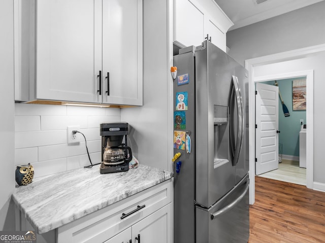 111 Walnut Ln, Williamson, GA 30292 - kitchen featuring stainless steel refrigerator with ice dispenser, decorative backsplash, wood finished floors, white cabinetry, and light stone counters