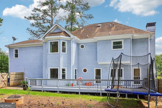771 James Cir, Lawrenceville, GA 30046 - rear view of property with a trampoline, stucco siding, a deck, a chimney, and fence