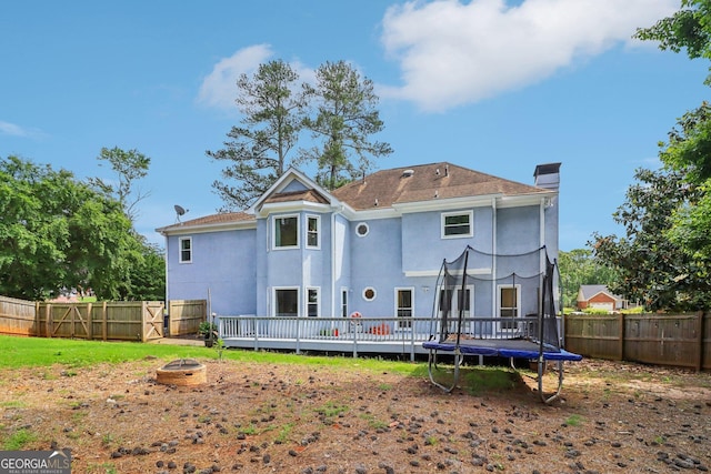 771 James Cir, Lawrenceville, GA 30046 - rear view of house featuring a fire pit, a trampoline, a fenced backyard, stucco siding, and a wooden deck