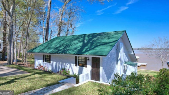 view of front of house featuring brick siding, a front yard, and metal roof