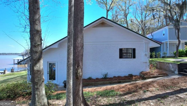 view of home's exterior with brick siding and a water view