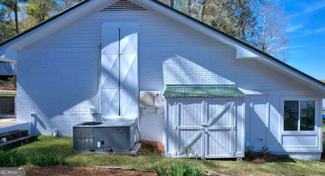 back of property featuring brick siding, central AC, an outbuilding, and a storage shed