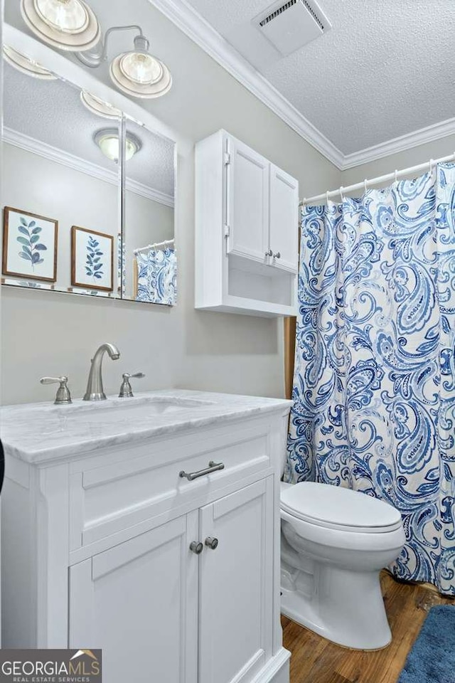 full bathroom with a textured ceiling, crown molding, wood finished floors, toilet, and vanity