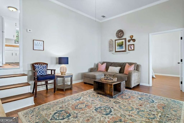 living area featuring wood finished floors, crown molding, and baseboards