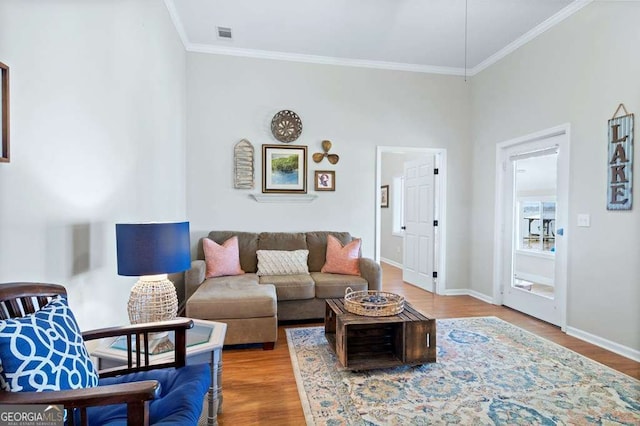 living area featuring wood finished floors, crown molding, and baseboards