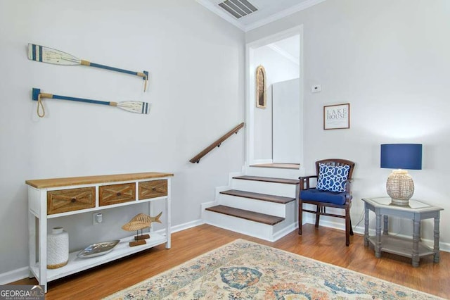 living area with crown molding, wood finished floors, stairs, and baseboards