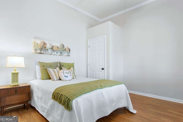 bedroom with ornamental molding, wood finished floors, and baseboards