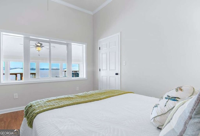 bedroom with ornamental molding, wood finished floors, baseboards, and a water view