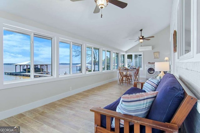 sunroom / solarium with washer / dryer, lofted ceiling, an AC wall unit, baseboards, and wood finished floors