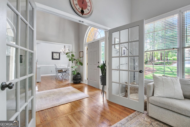 entryway featuring french doors, a chandelier, wood finished floors, and a high ceiling