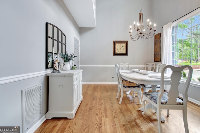 dining space featuring a chandelier, light wood finished floors, and baseboards