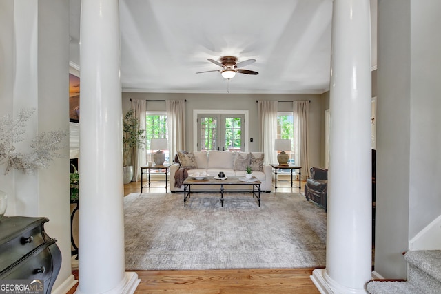 living room with ornate columns, ceiling fan, wood finished floors, and stairway