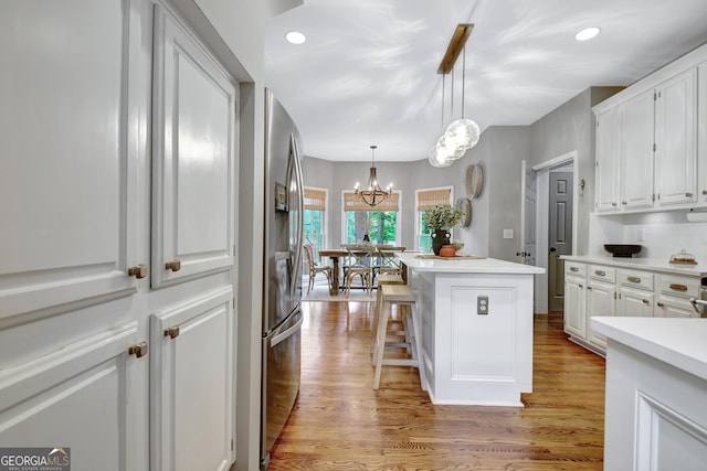 kitchen with white cabinets, a kitchen island, light countertops, light wood finished floors, and recessed lighting