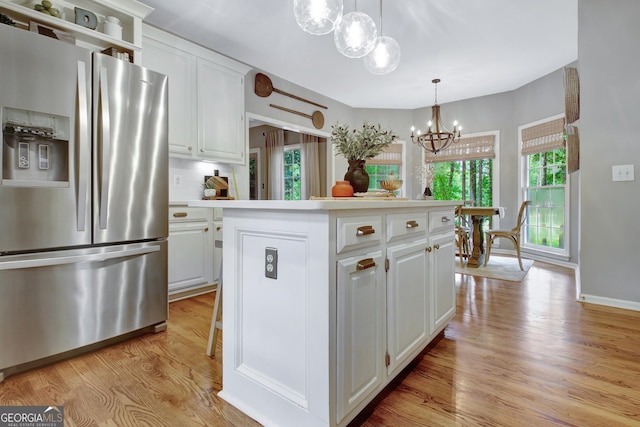 kitchen featuring stainless steel refrigerator with ice dispenser, a chandelier, light wood-style flooring, white cabinetry, and a center island
