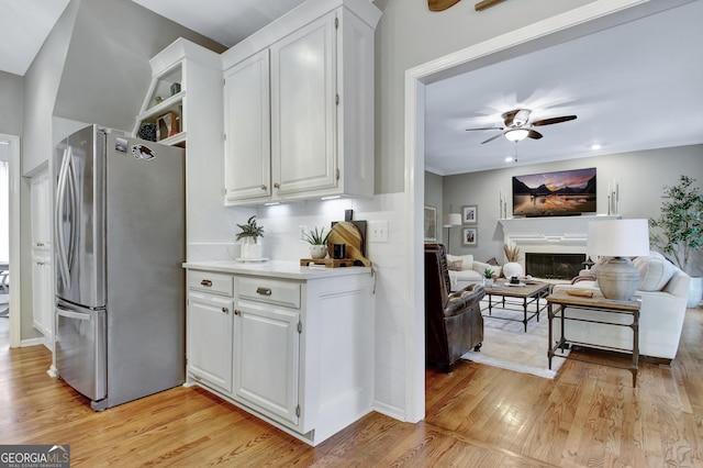 kitchen with freestanding refrigerator, light wood-style flooring, a ceiling fan, white cabinetry, and light countertops