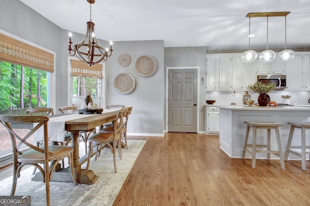 kitchen featuring stainless steel microwave, white cabinetry, a chandelier, light countertops, and light wood finished floors