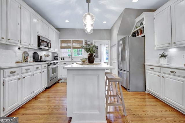 kitchen featuring stainless steel appliances, a kitchen island, white cabinets, light countertops, and recessed lighting