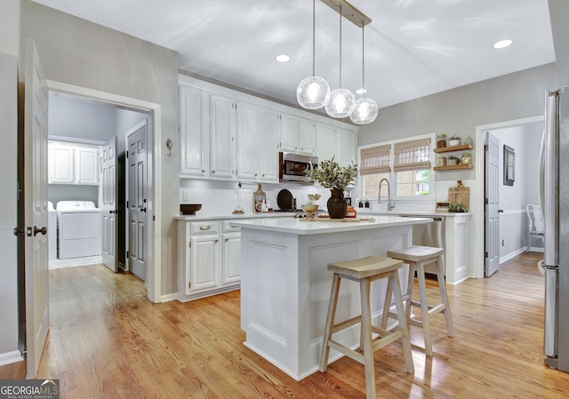 kitchen featuring appliances with stainless steel finishes, a sink, white cabinetry, a center island, and recessed lighting