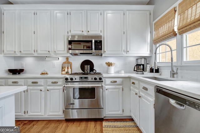 kitchen with appliances with stainless steel finishes, a sink, and white cabinets