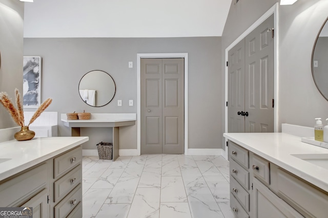 bathroom featuring marble look tiles, baseboards, and two vanities