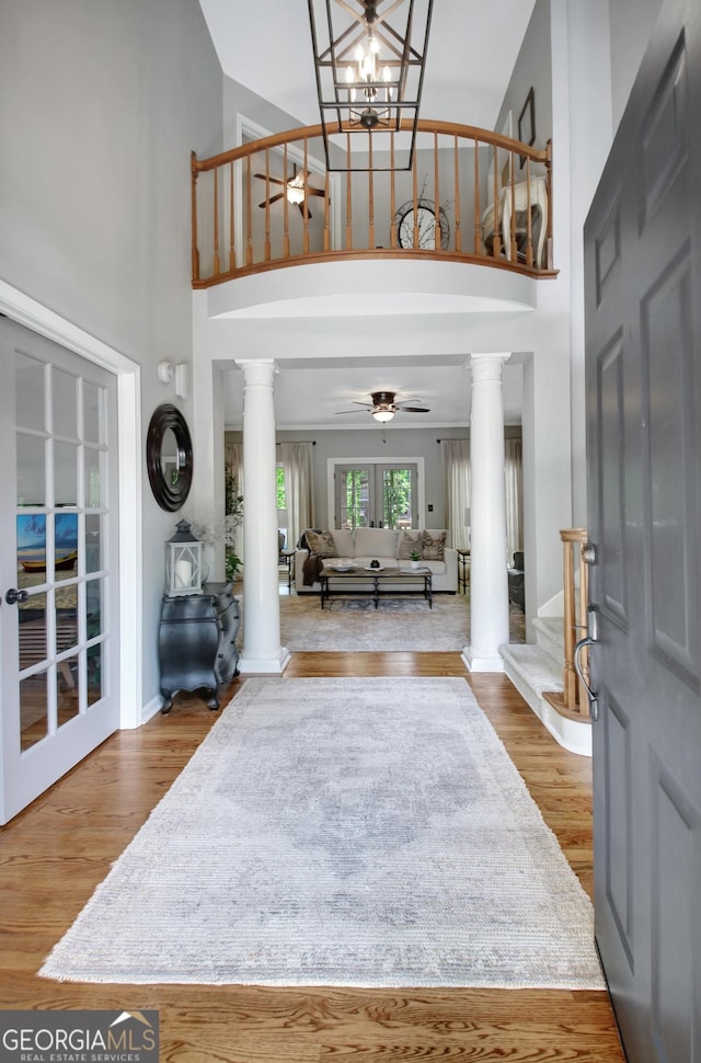 foyer with ornate columns, a ceiling fan, high vaulted ceiling, and wood finished floors
