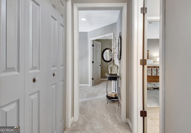 hallway featuring light carpet and baseboards