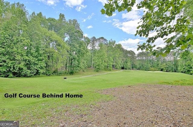 surrounding community with golf course view, a yard, and view of scattered trees