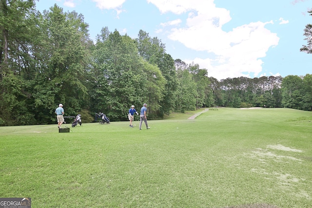 view of property's community with a lawn, view of scattered trees, and golf course view