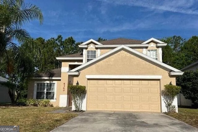traditional home with concrete driveway, stucco siding, an attached garage, and a front yard