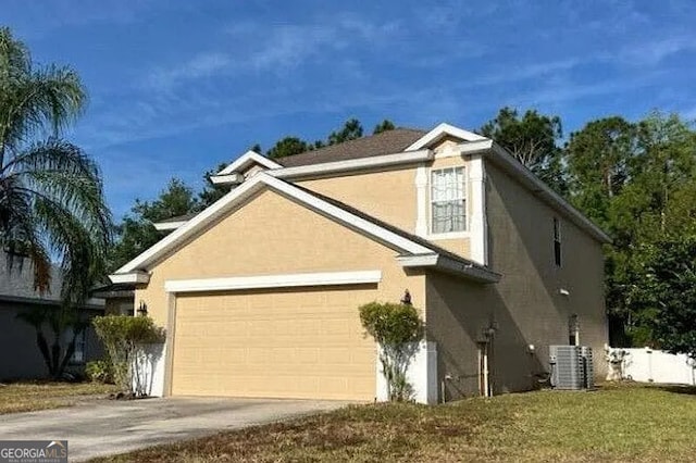 view of front of house with stucco siding, driveway, an attached garage, and central AC unit