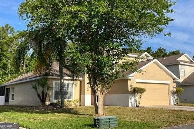 view of front facade with an attached garage, stucco siding, a front lawn, and driveway