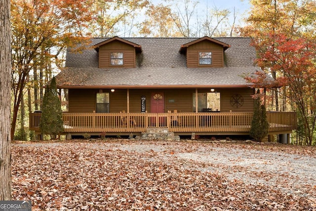 chalet / cabin featuring a shingled roof and covered porch