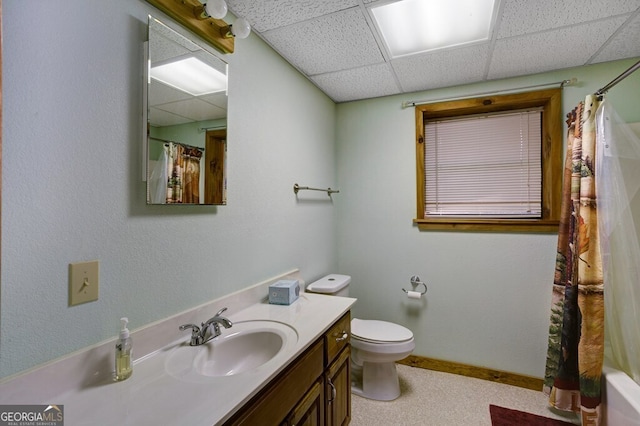 full bathroom with a shower with curtain, toilet, vanity, a drop ceiling, and baseboards