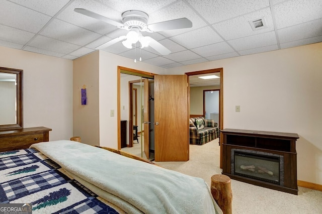 carpeted bedroom with a paneled ceiling, a closet, a ceiling fan, and a fireplace