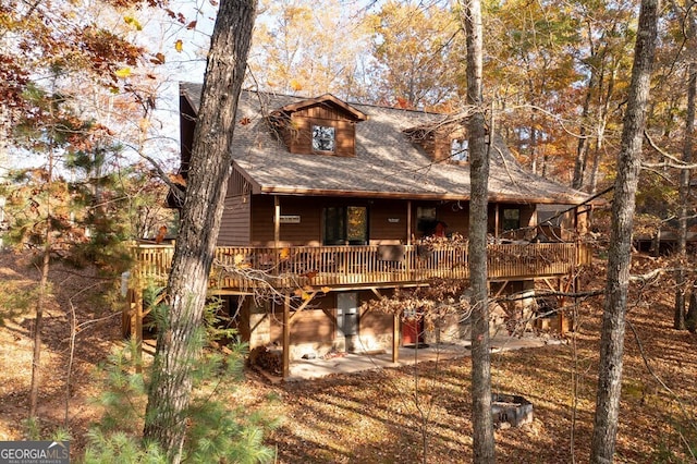 back of property with a wooden deck and roof with shingles