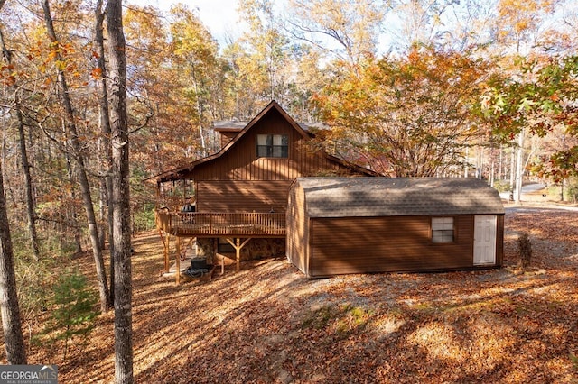 view of side of home with a deck, an outdoor structure, and a shed