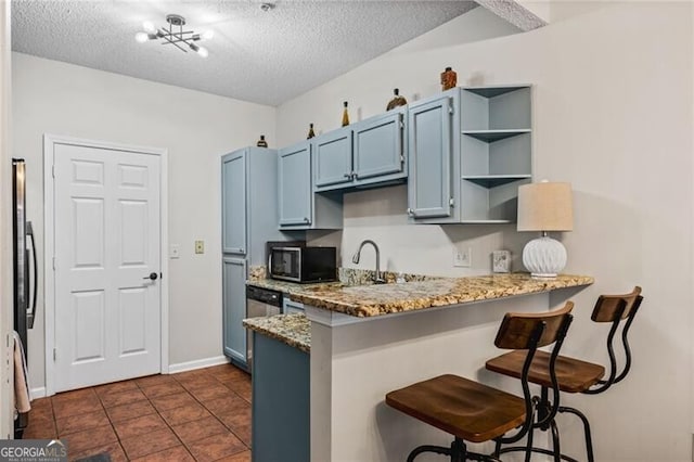 508 Vinings Forest Ct SE, Smyrna, GA 30080 - kitchen with stainless steel microwave, a peninsula, a breakfast bar area, light stone counters, and blue cabinets