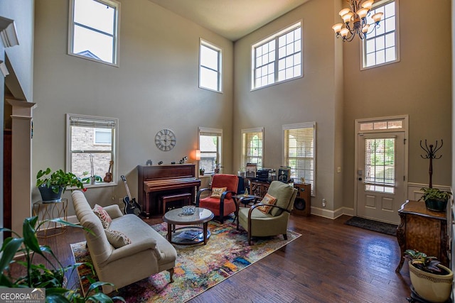 living area with a high ceiling, wood finished floors, a chandelier, plenty of natural light, and baseboards