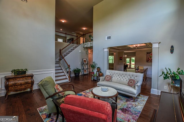 living room with a high ceiling, stairs, wood finished floors, and ornate columns