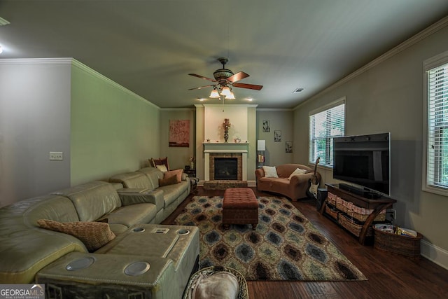 living area with a brick fireplace, wood finished floors, ceiling fan, plenty of natural light, and ornamental molding