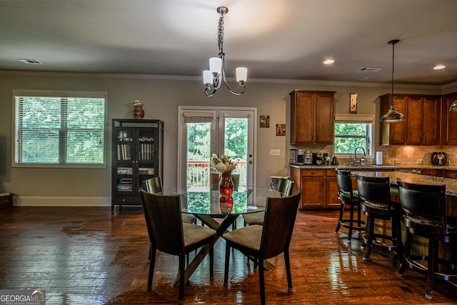 dining space featuring a chandelier, dark wood finished floors, baseboards, crown molding, and recessed lighting