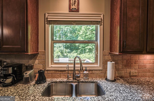 kitchen featuring a sink, tasteful backsplash, dark stone countertops, and dark brown cabinetry